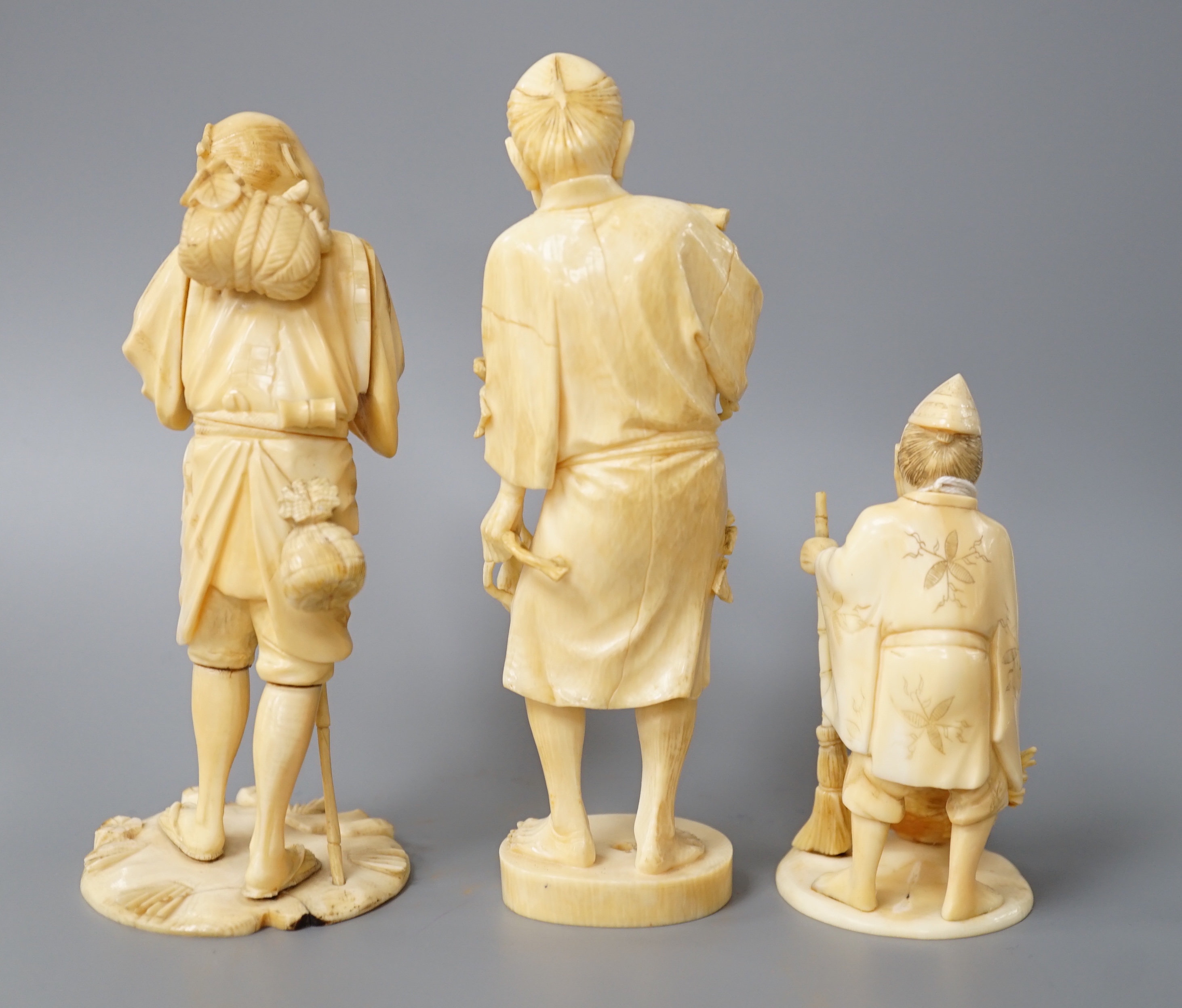 A 19th century Japanese ivory okimono of a gentleman holding a branch, another sectional figure of a gentleman with a walking stick, both signed and another 20th century okimono. Tallest 15.5cm